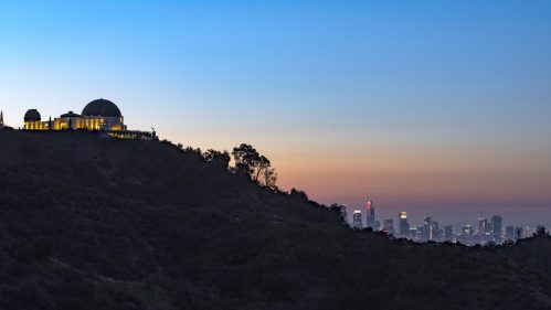 Griffith Observatory silhouetted against a twilight sky, with the Los Angeles skyline in the background.