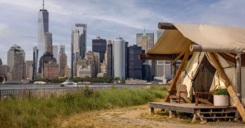 A scenic shot of a canvas tent on Governors Island in New York, with a beautiful view of the New York City skyline.