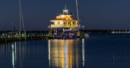 The Choptank River Lighthouse in Cambridge, Maryland at night, illuminating the river.