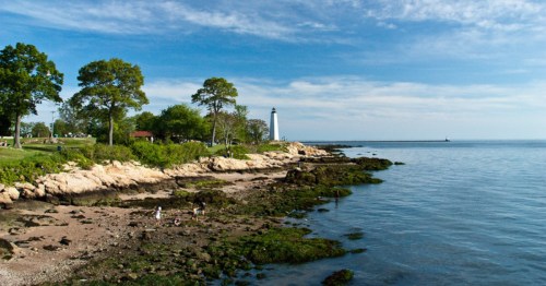 A sunny view of Lighthouse Point Park in New Haven, Connecticut with the New Haven Lighthouse in the background.