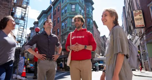 A group of guests and a tour guide stand outside local buildings during the North End Food, History & Italian Bites food tour in Boston, Massachusetts.