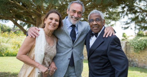 A smiling group of diverse seniors dressed in formal attire at a sunny outdoor gathering in Michigan.