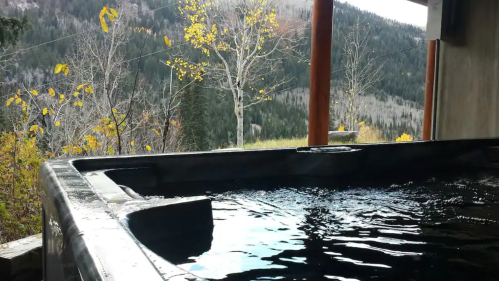 A hot tub with water, surrounded by autumn trees and mountains in the background.