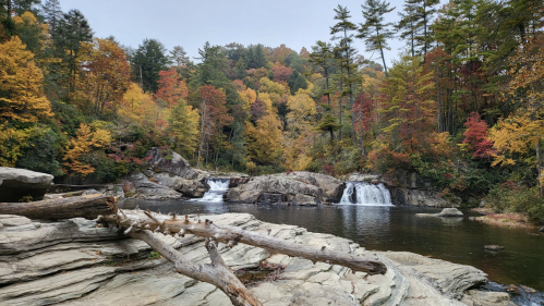 A serene waterfall surrounded by colorful autumn foliage and rocky terrain, reflecting the beauty of nature.