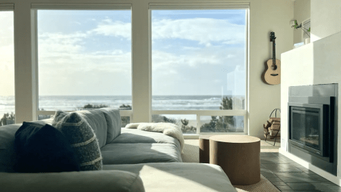 Cozy living room with a view of the ocean, featuring a sofa, coffee table, and a guitar on the wall.