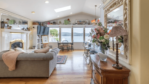 Cozy living room with a view, featuring a sofa, dining area, and decorative flowers by the window.