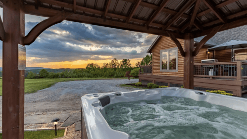 A hot tub under a wooden gazebo with a scenic sunset and green landscape in the background.