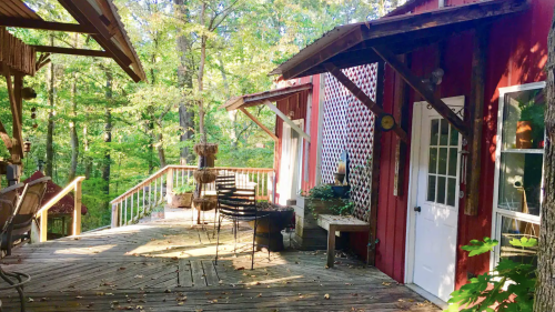 A rustic wooden deck with red cabins surrounded by lush green trees in a serene outdoor setting.
