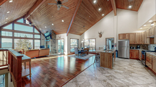 Spacious, modern living area with wooden beams, large windows, and a kitchen, featuring a cozy dining space.