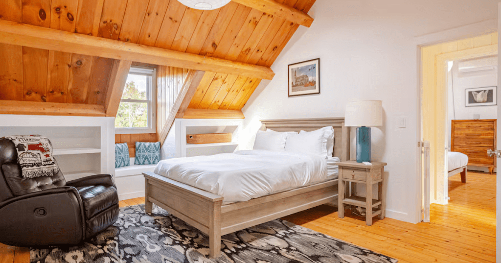 A bedroom with a queen bed and a leather reclining chair at the Meryall Cabin Airbnb in New Milford, Connecticut,