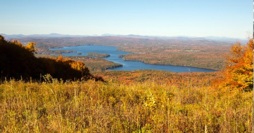 An overlook of Sunapee Lake from the top of Mount Sunapee in New Hampshire, covered in golden fall foliage.