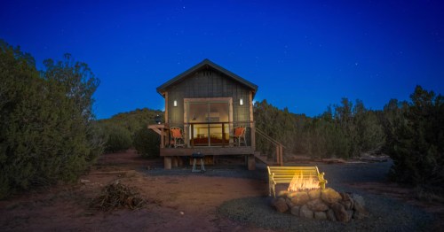 View at dusk of off-grid vacation rental cabin Sunset Cabin in Show Low, AZ, with a fire burning in the outdoor fire pit.