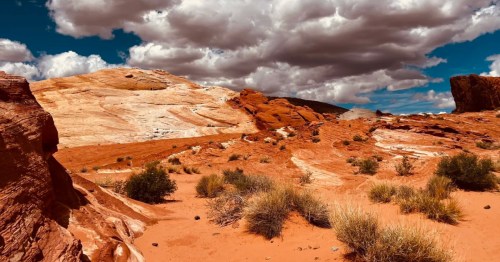 A striking red rock landscape with grey and white clouds along the Fire Wave, White Domes, and Seven Wonders Loop in Nevada's Valley of Fire State Park.