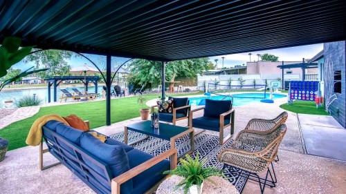 Cozy outdoor seating area with a pool view, featuring a rug, plants, and a shaded patio.