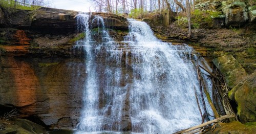 Multi-tiered white water of Brandywine Falls in Ohio, showcasing spring runoff and rocky cliffs.