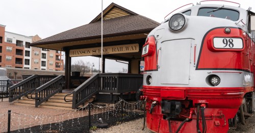 a red and white train pulls up to the branson missouri train station