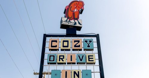 Two hot dogs embrace above a Coy Drive In sign.