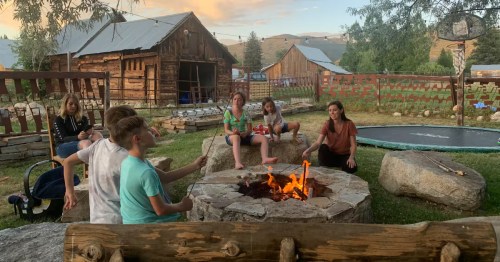 a family sits around a fire pit roasting marshmallows at a farmstay airbnb in fairview utah
