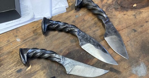 Hand-forged custom knives with twisted handles on a workbench in Festus, MO