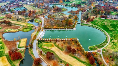 Aerial view of a scenic park with ponds, walking paths, and autumn foliage in vibrant colors.
