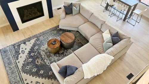 A spacious living room featuring a large sectional sofa, a coffee table, and a dining area with white chairs.