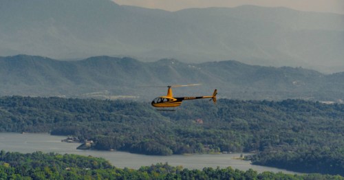 Bright yellow helicopter set amidst a stunning backdrop of the mountains and a lake in TN.