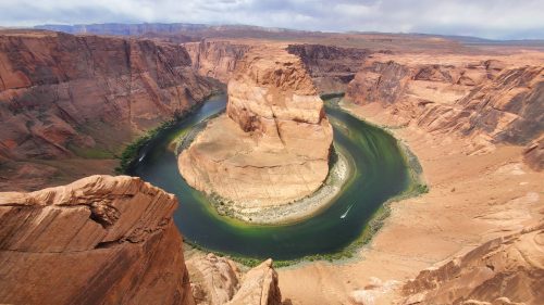 Aerial view of Horseshoe Bend, showcasing a winding river surrounded by steep red rock cliffs and desert landscape.