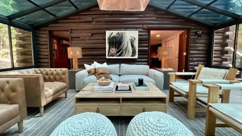 Cozy living room with a glass ceiling, featuring a sofa, armchairs, wooden coffee table, and stylish decor.