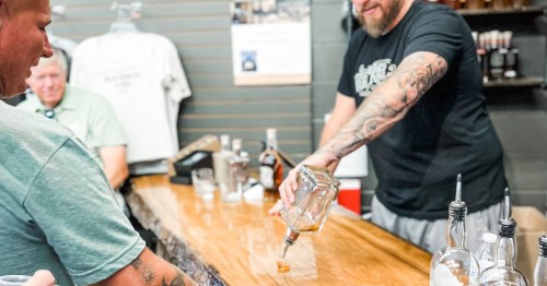 Bartender pouring a bourbon flight for customers at a rustic bar in Deadwood, SD.
