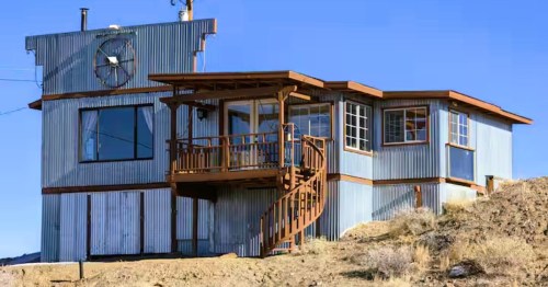 Views of Eclectic Desert Home in Goldfield, NV, a unique, corrugated metal Airbnb, featuring a spiral staircase and large windows.