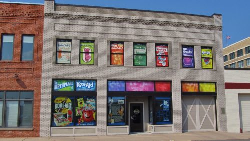 A brick building featuring colorful Kool-Aid advertisements on the windows and walls.