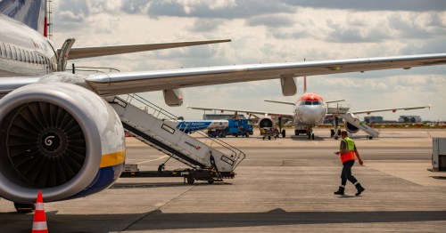 Close-up of a commercial airplane parked at an airport terminal gate with a boarding stair truck attached during daytime operations.