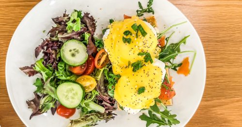 A vibrant, breakfast dish with salmon eggs Benedict and a fresh, garden salad. This is a brunch dish, true comfort food in Michigan at Morning Belle in Grand Rapids.