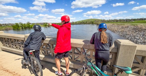 A family with bikes enjoying the views of the Cedar River along the Cedar Valley Nature Trail, an Iowa rail trail in Cedar Rapids.