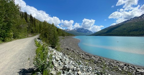 The Eklutna Lakeside Trail travels along bright blue water in Alaska.