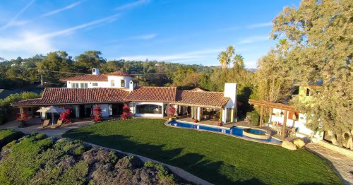 The exterior of a waterfront Airbnb in Santa Barbara, California, with a pool and a large grassy yard.