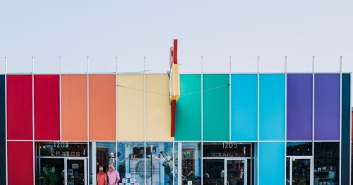 Two small business owners stand in front of a rainbow curiosities shop in Oklahoma City, OK.