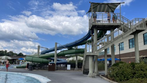A water park featuring a large slide, pool area, and cloudy blue sky in the background.