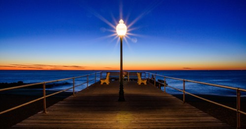 A nighttime view of the Ocean Grove pier in New Jersey, illuminated. by a lamppost.