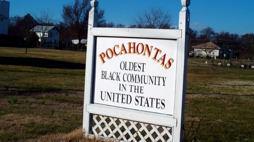 Sign reading "Pocahontas: Oldest Black Community in the United States" in a grassy area with trees in the background.