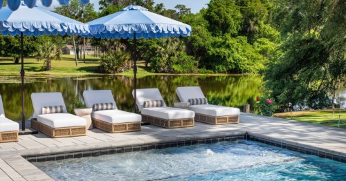 Four white lounge chairs under umbrellas sit next to an Airbnb with a pool in Georgia.