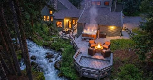 An aerial view of a waterfront Airbnb in Colorado, surrounded by a dense wooded area.