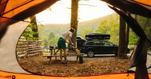 Perspective of a camper setting up a site as seen from an orange tent with a mountain ridge in the distance