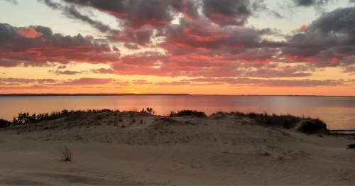 The sun sets on a dune hike in North Carolina that looks out toward the ocean.