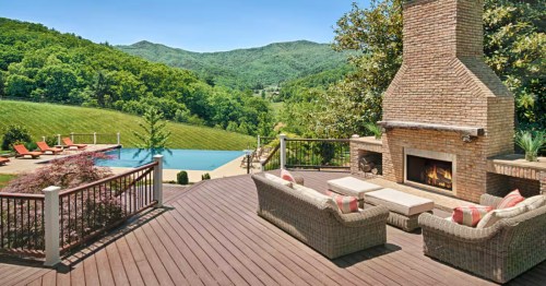Deck with large fireplace and outdoor furniture leading down to an infinity-edge pool at an Airbnb in North Carolina