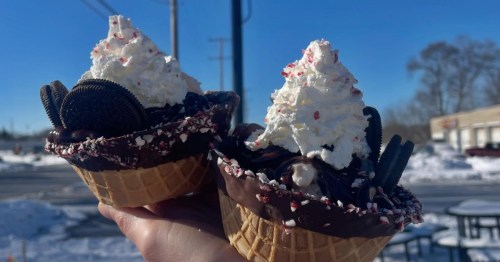 Two peppermint sundaes being held in front of the signage at LeDuc's Frozen Custard in Wales, Wisconsin