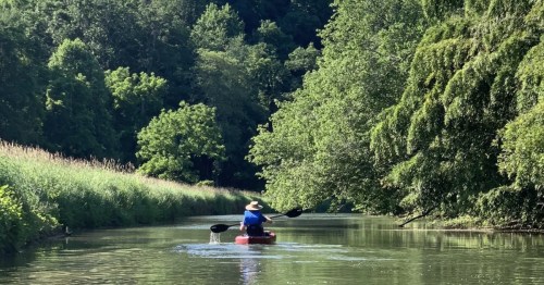 A paddler makes their way down the calm creek at Eden Mill Nature Center on a lovely summer day