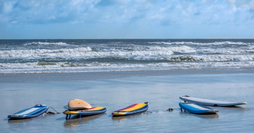 A group of surf boards lay on the sand at New Smyrna Beach, Florida