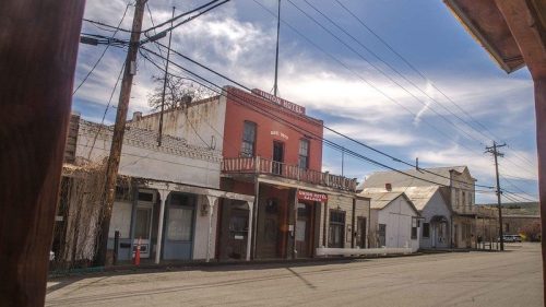 Historic buildings line a quiet street, featuring the prominent red facade of the Washington Hotel under a blue sky.