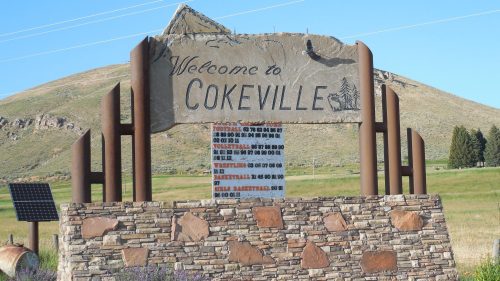 Welcome sign for Cokeville, featuring stone and metal design with a mountain backdrop.
